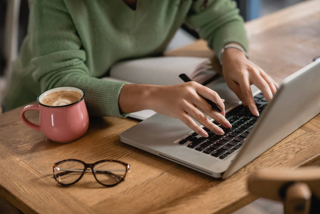 Writing an article on a laptop beside a coffee