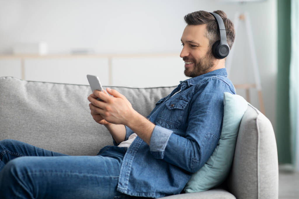 Positive bearded man with headset and mobile phone