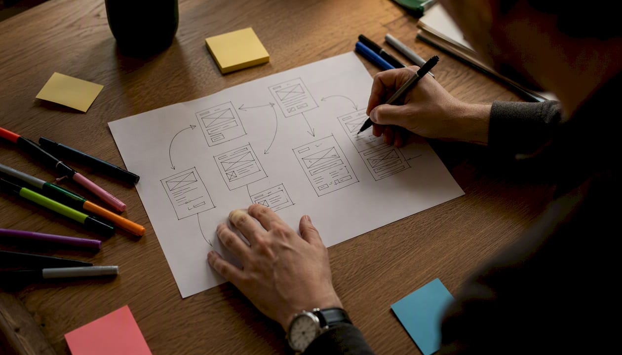 Hands sketching low-fidelity website prototype on paper