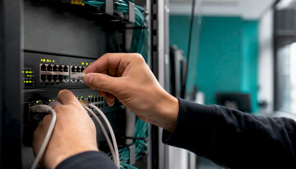 Hands connecting network cable in server room